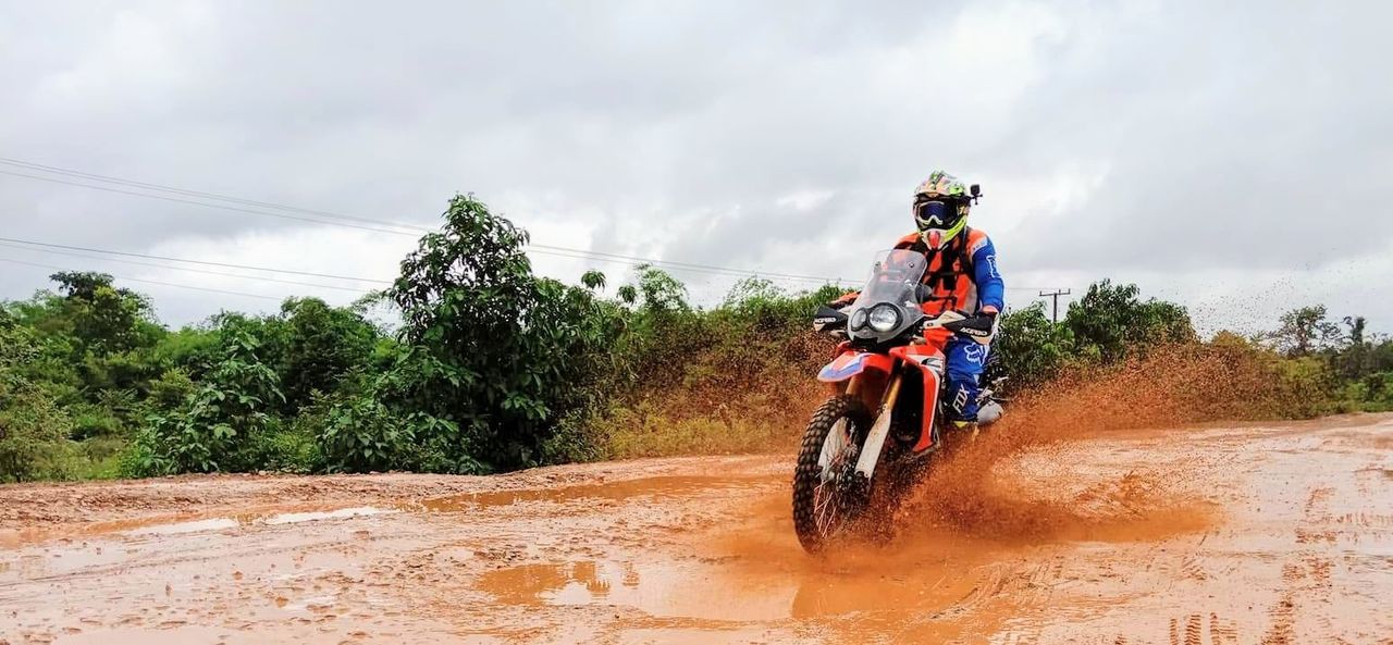 transportation, motion, helmet, riding, ride, nature, headwear, mode of transportation, full length, sport, cloud - sky, speed, sky, plant, road, sports helmet, tree, day, one person, crash helmet, skill, outdoors, mature men