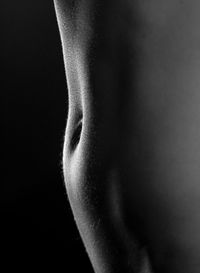 Midsection of woman abdomen against black background