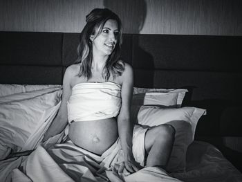 Young woman sitting on bed at home
