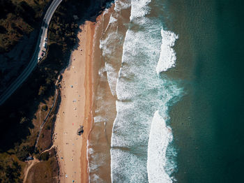 High angle view of beach with waves and surfers