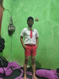 Portrait of boy standing against wall