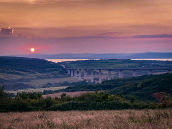 Scenic view of field against sky at sunset