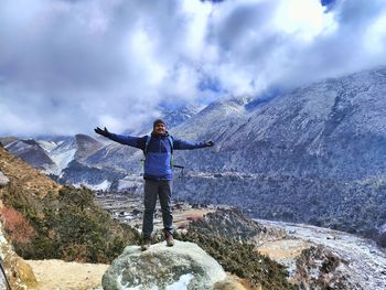 Rear view of man standing on mountain against sky