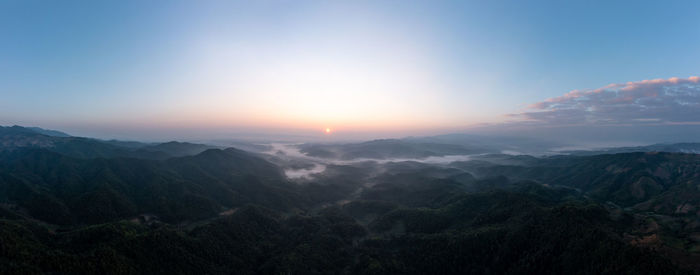 Mountain fog in the valley silhouette and morning sunlight blue sky background aerial view 