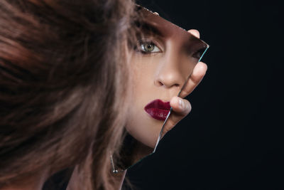 Close-up of young woman looking away against black background