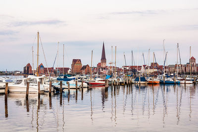 Sailboats moored at harbor against sky