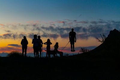 Silhouette of tourists standing on mountain during sunset