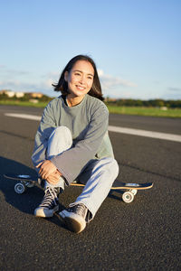 Portrait of young woman sitting on road