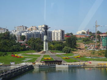 Buildings by river against sky in city