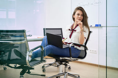 Portrait of young woman using mobile phone while sitting at airport