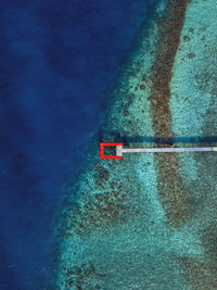 Red pier over turquoise sea at thulusdhoo island in kaafu atoll, maldives