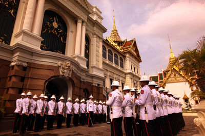 Army soldiers standing by historic building during sunset