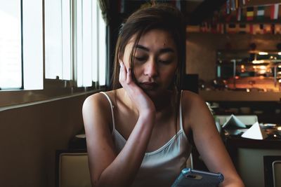 Woman using mobile phone while sitting in restaurant