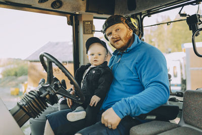 Portrait of father and son sitting in tractor