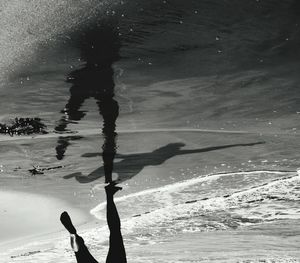Low section of silhouette woman swimming in sea