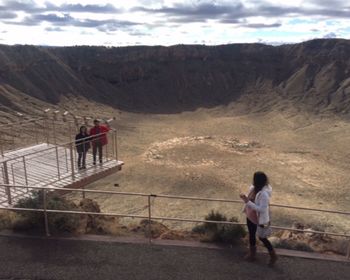 People standing on steps by mountains against sky