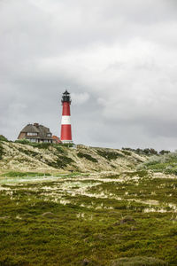 Lighthouse on landscape against sky