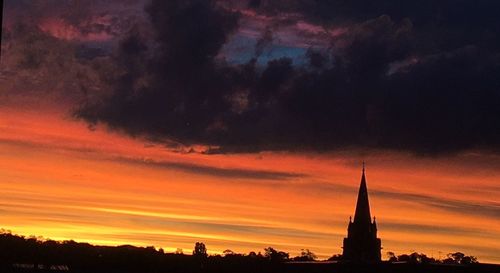 Silhouette of temple against cloudy sky during sunset