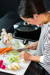 Woman slicing vegetables while cooking stew. close up of woman hands cutting vegetables