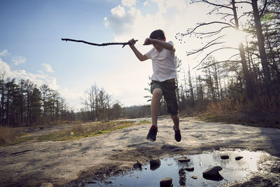 Boy jumping over puddle on arabia mountain against cloudy sky