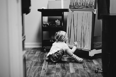 Rear view of girl sitting on floor at home