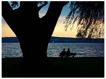 Silhouette of people on lakeshore at sunset