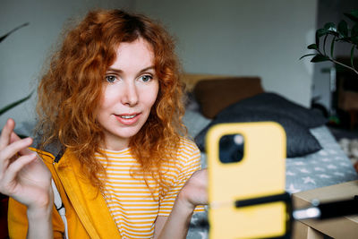 Portrait of young woman using mobile phone at home