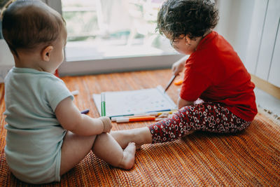 Cute childs sitting on drawing at home