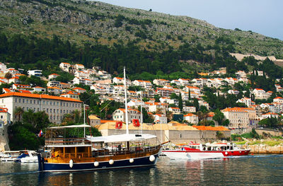 Boats moored in river by city against sky