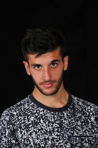 Portrait of young man against black background