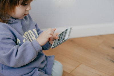 Little girl in violet hoodie using a phone on white background . high quality photo