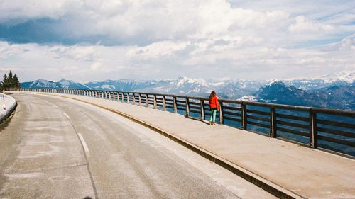 Rear view of woman standing on bridge by mountains