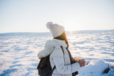 Rear view of woman looking at sea against sky during winter