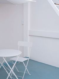 Empty chairs and table against white wall at home