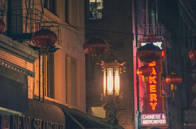 Low angle view of illuminated lanterns hanging on street by buildings
