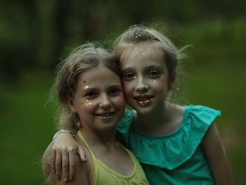 Close-up portrait of smiling sisters wearing make-up outdoors