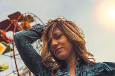 Portrait of beautiful woman against sky during sunset in amusement park