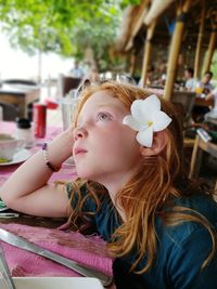 Side view of thoughtful girl looking away while sitting in restaurant