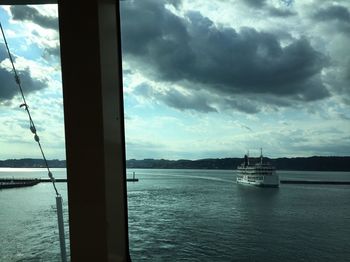 Boats in sea against cloudy sky