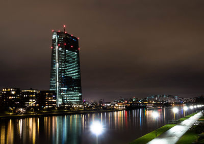 Scenic view of river by illuminated building in city at night