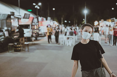 Young woman wear protection mask touring in night market , travel and recreation concept