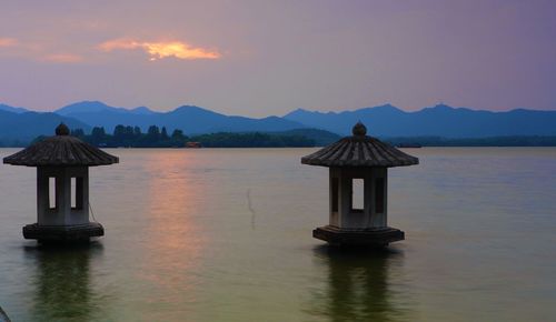 Lifeguard hut in lake against sky during sunset