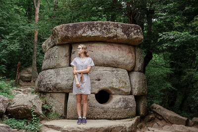 Portrait of woman standing on rock against trees