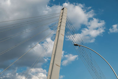 Low angle view of suspension bridge against cloudy sky