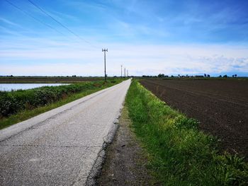 Road amidst field against sky