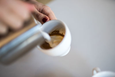 Close-up of hand pouring milk in coffee