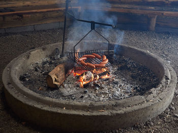 High angle view of sausages on barbecue grill in fire pit