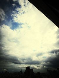 View of cityscape against cloudy sky