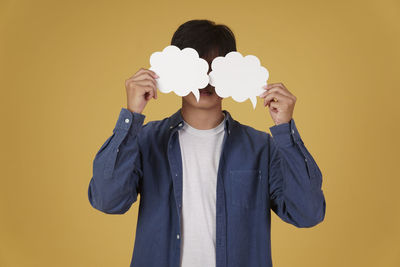 Full length of young man standing against yellow background