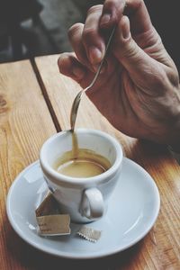 Close-up of hand holding coffee cup on table